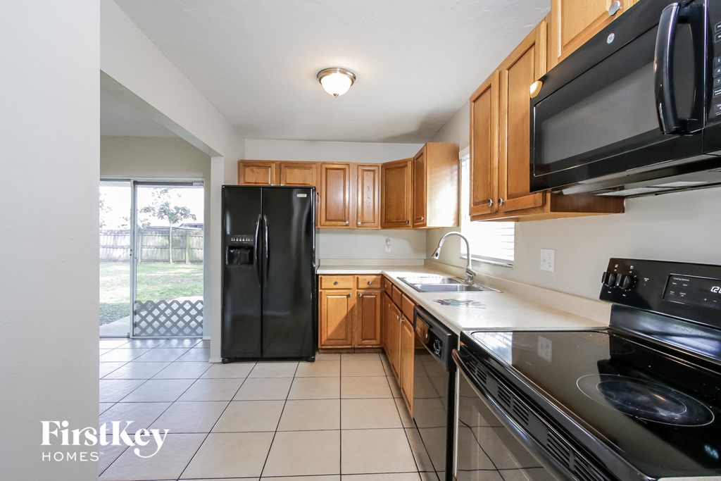 A kitchen with a black fridge and black microwave.