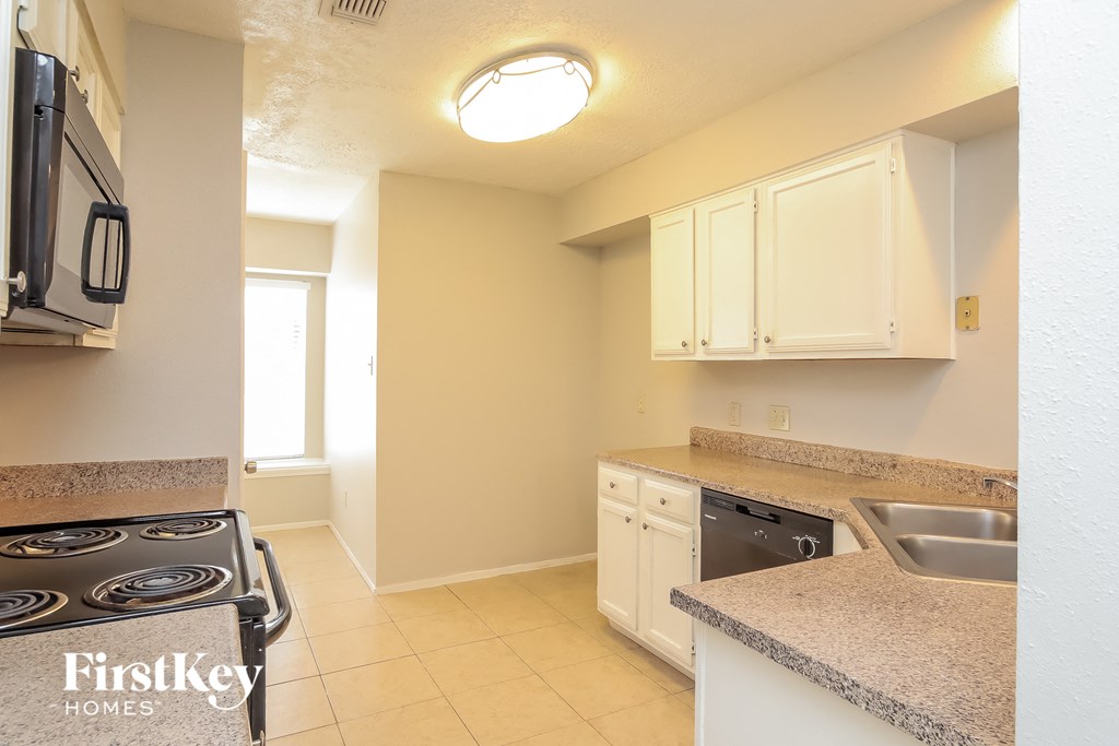a kitchen with white cabinets and granite counter tops and a stove top oven
