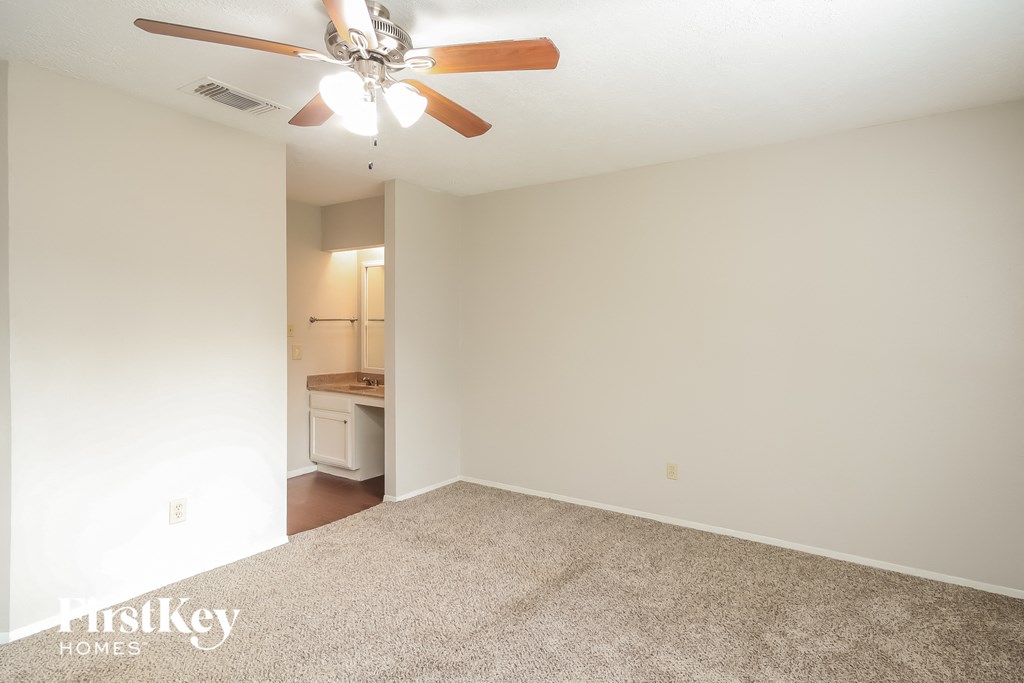 an empty living room with a ceiling fan and a carpet