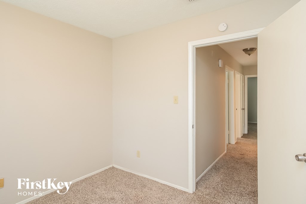 a bedroom with a door to a hallway and a carpeted floor