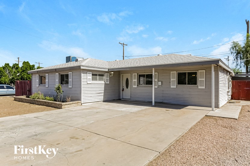 a small gray house with a concrete driveway
