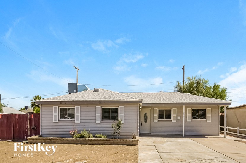 a white house with a fence and a blue sky