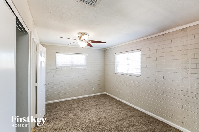 a bedroom with a ceiling fan and a white brick wall