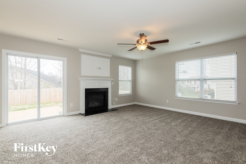 A spacious living room with a fireplace and a ceiling fan.