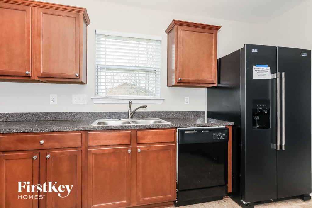 A kitchen with wooden cabinets and a black fridge.