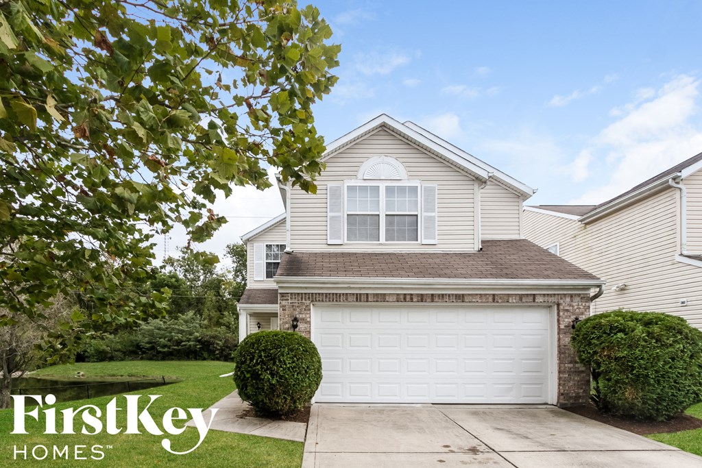 a white house with a white garage door in front of a lawn