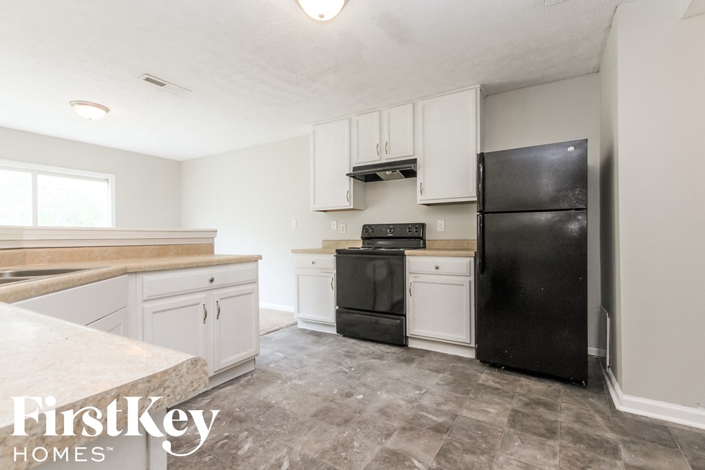 a kitchen with white cabinets and a black refrigerator