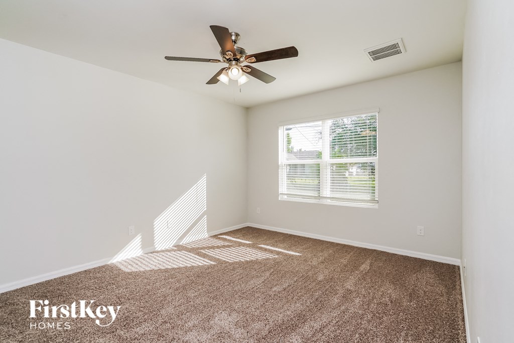a living room with carpet and a ceiling fan