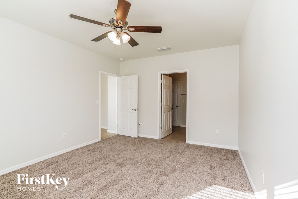 a spacious living room with white walls and a ceiling fan