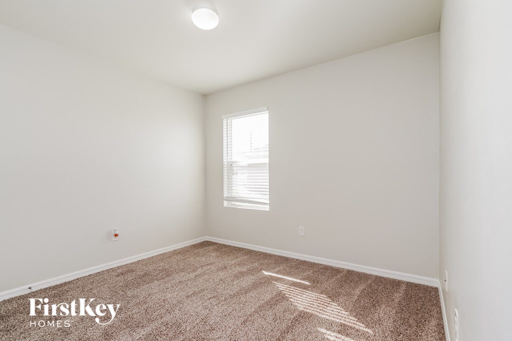 a bedroom with white walls and carpet and a window