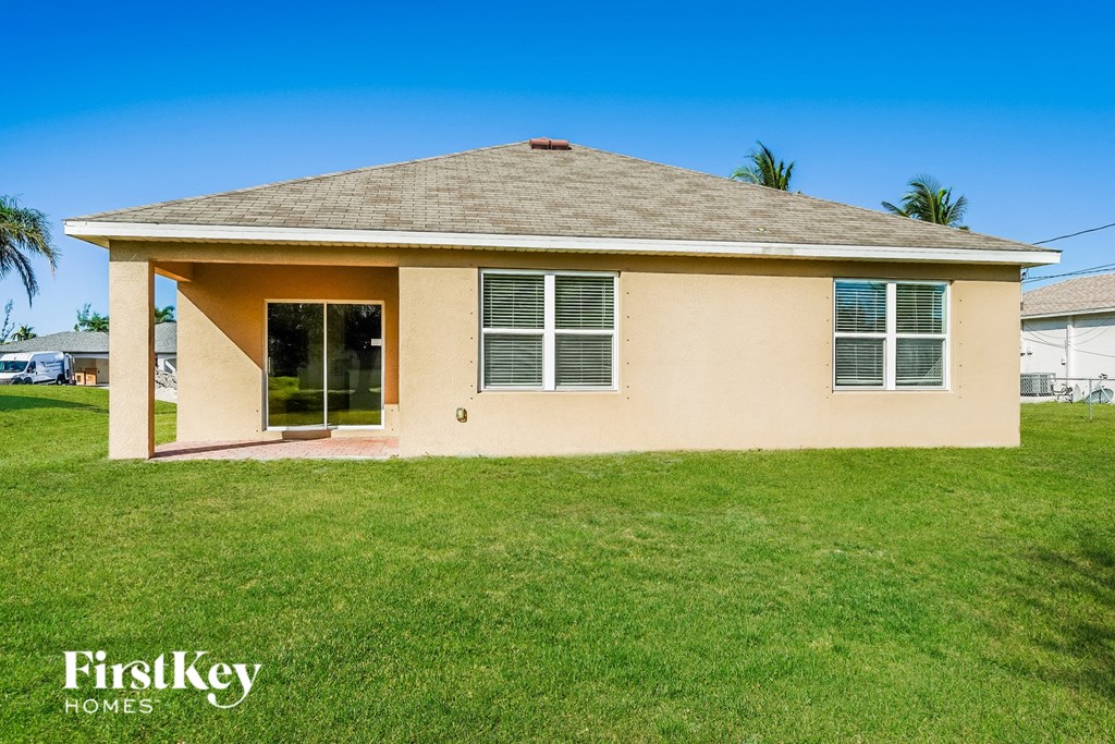 a beige house with a grass lawn and a palm tree