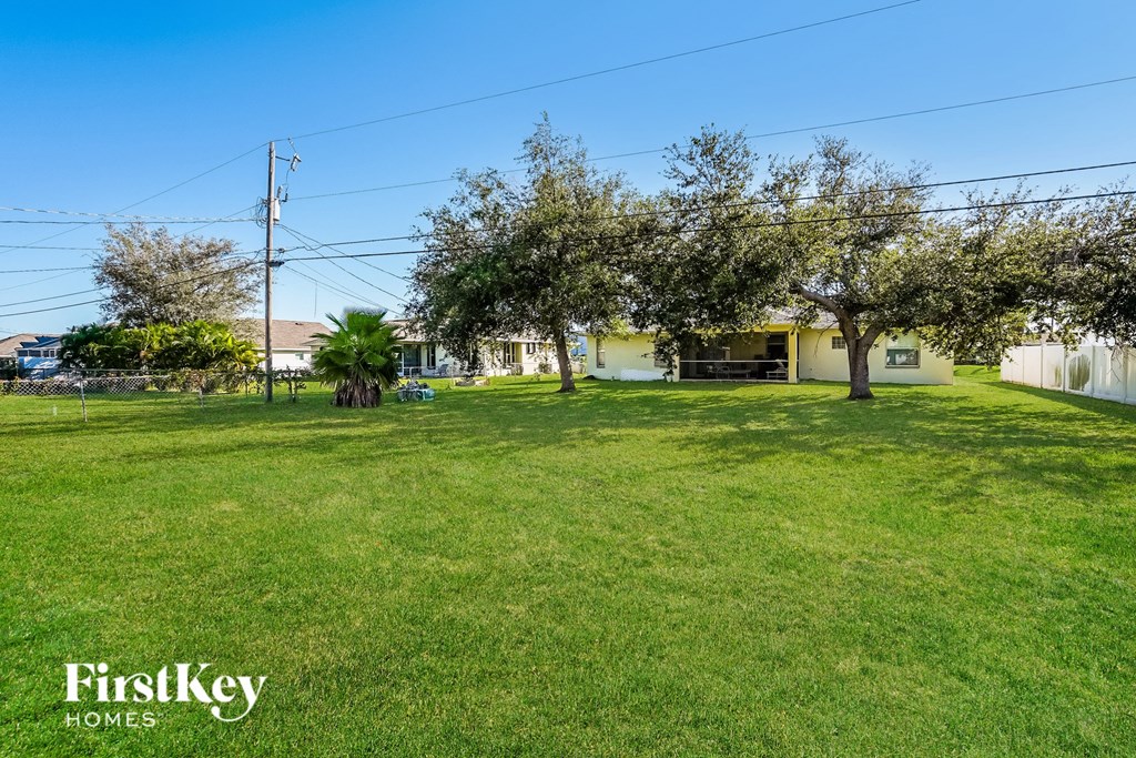 a large lawn with trees and a house in the background