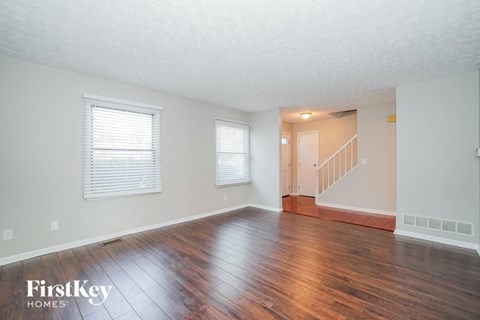 the living room and dining room with wood floors and white walls
