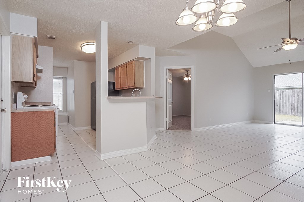 an empty kitchen and living room with white tiled flooring