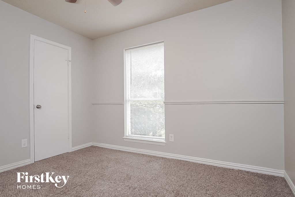 a bedroom with white walls and a window and a door