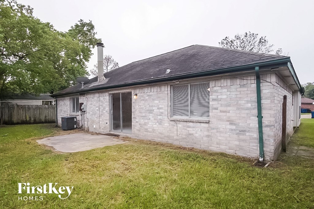 the backyard of a small brick house with a yard and grass