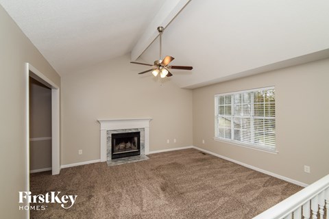 A living room with a fireplace and a ceiling fan.