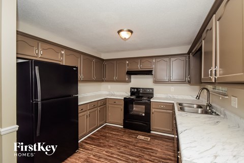 A kitchen with a black fridge and wooden floors.