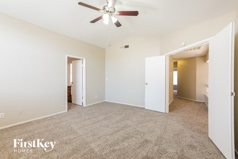 a spacious living room with carpet and a ceiling fan