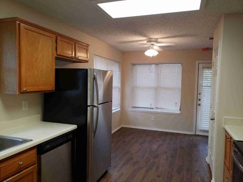 A kitchen with a black refrigerator and wooden cabinets.
