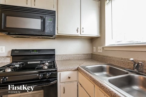 A kitchen with a black stove top oven and a black microwave above it.