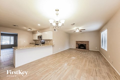 A spacious living room with wooden flooring and a fireplace.