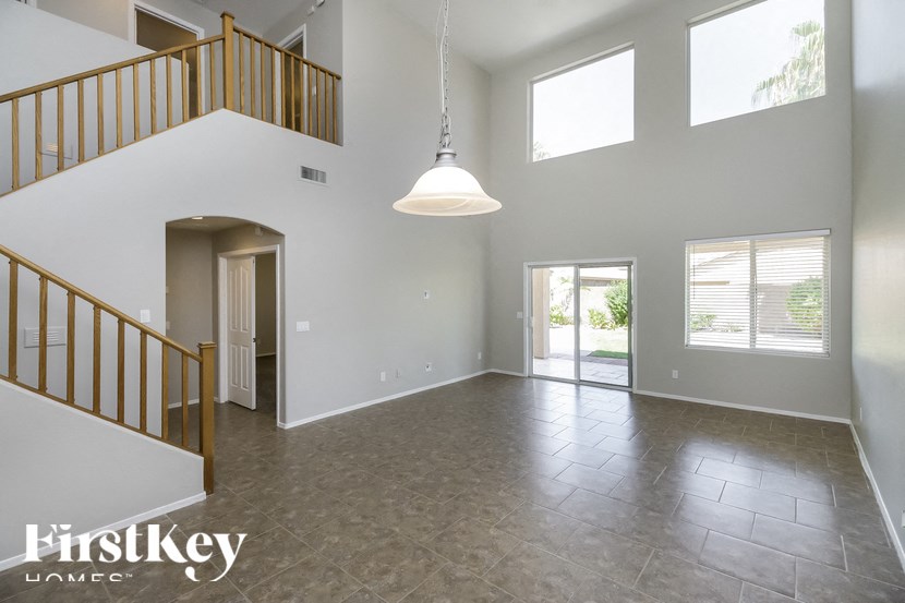 A spacious room with a staircase and a hanging light fixture.