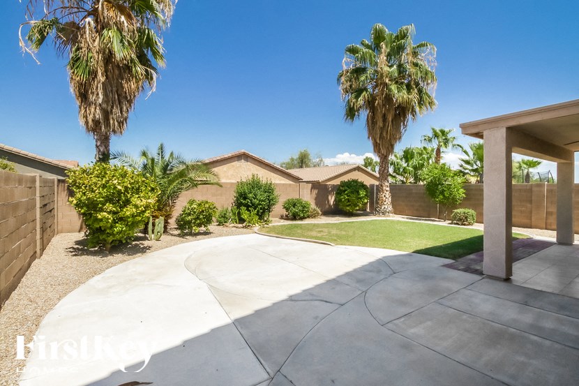 A house with a driveway and palm trees in the background.