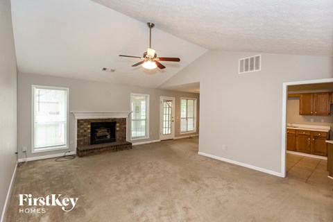 an empty living room with a fireplace and a ceiling fan