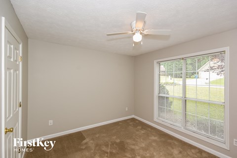 a bedroom with a large window and a ceiling fan