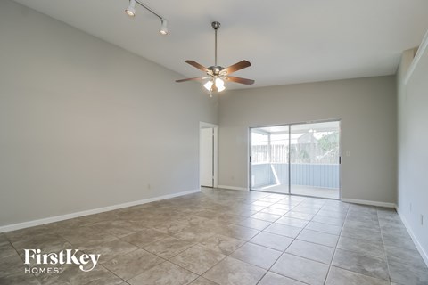 an empty living room with a ceiling fan and tile flooring