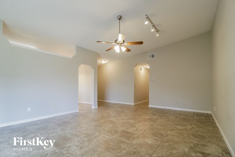 the spacious living room with tile flooring and a ceiling fan
