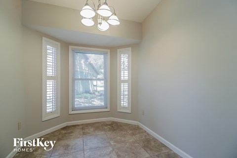 an empty dining room with three windows and a chandelier
