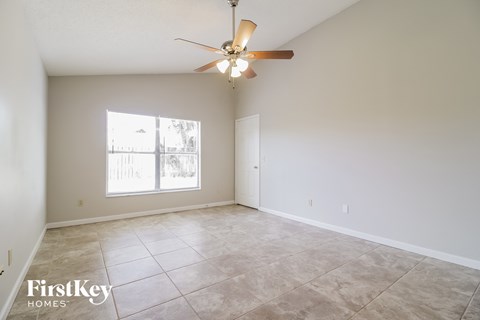 the living room and dining room of an empty house with a ceiling fan