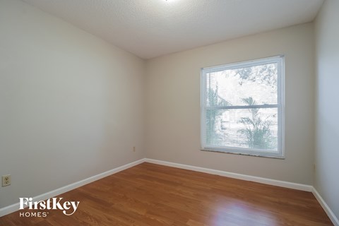 a bedroom with a window and wooden floors