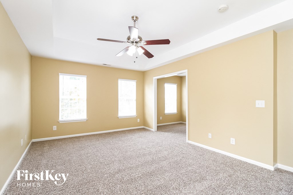 A spacious room with a ceiling fan and carpeted floor.