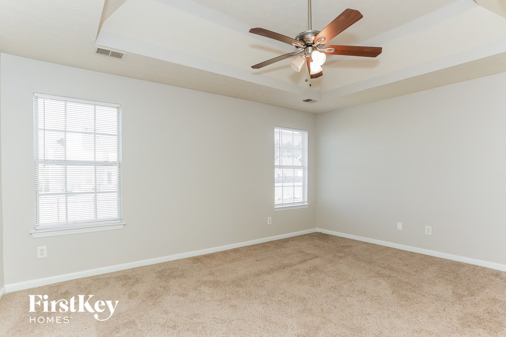 an empty room with a ceiling fan and two windows