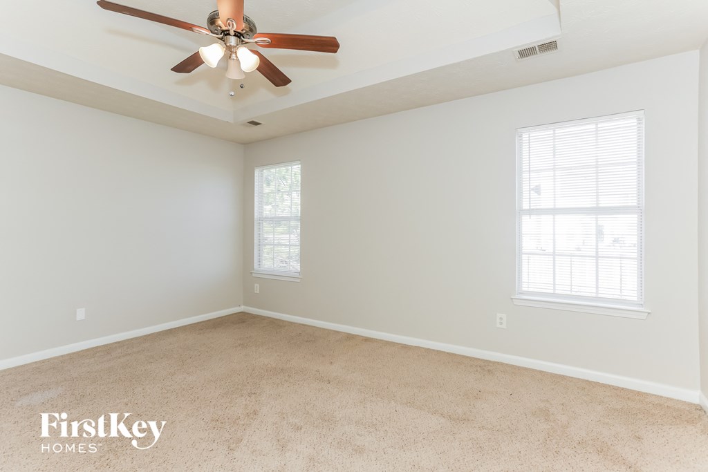 an empty room with a ceiling fan and two windows