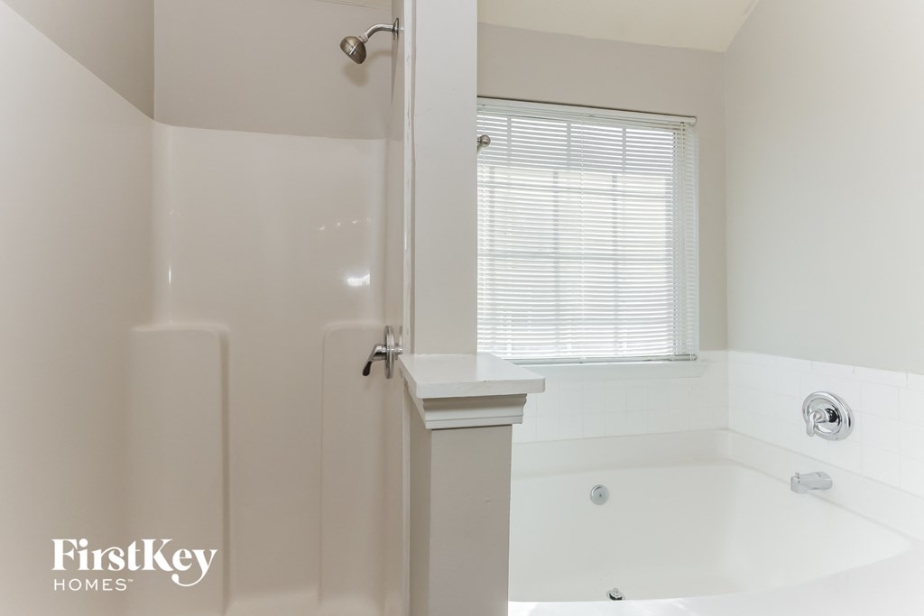 a bathroom with a tub and a shower and a window