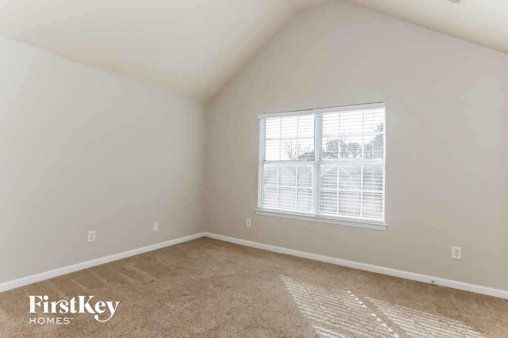 a bedroom with a large window and a carpeted floor
