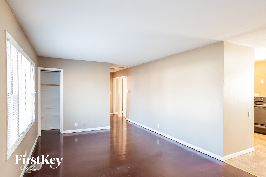 an empty living room with wood floors and white walls