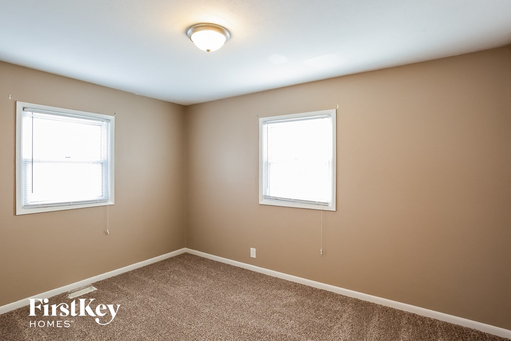 a bedroom with two windows and a carpet