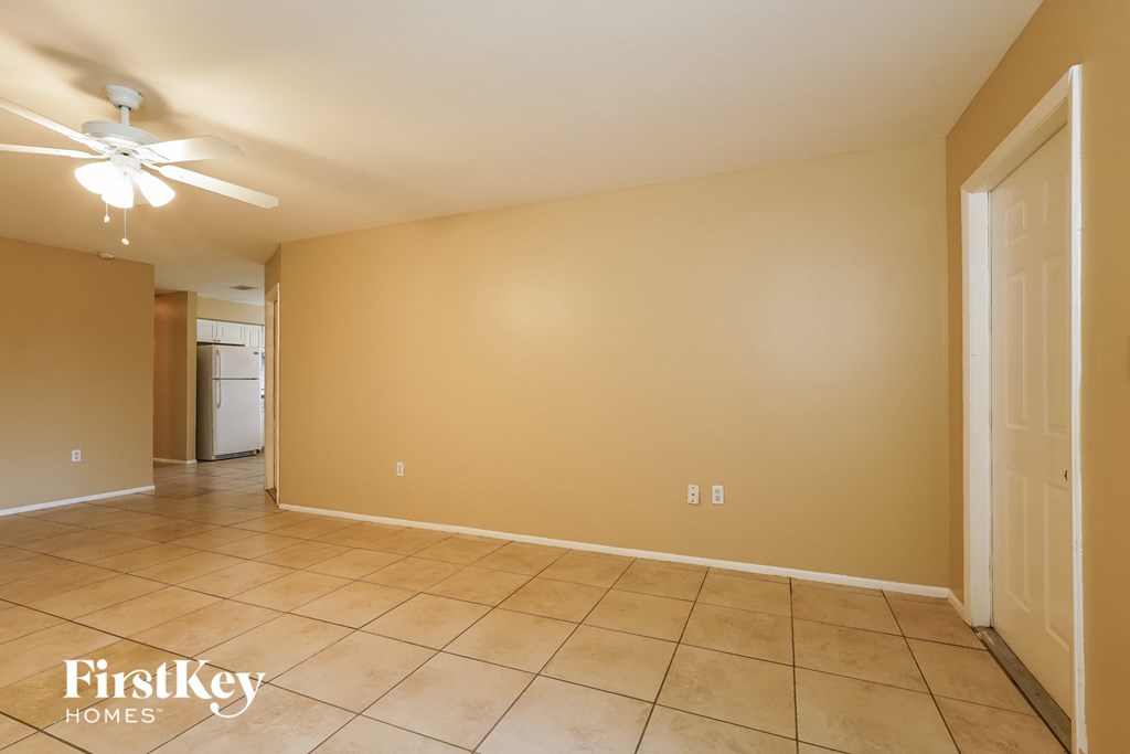 a empty living room with tiled floors and a ceiling fan