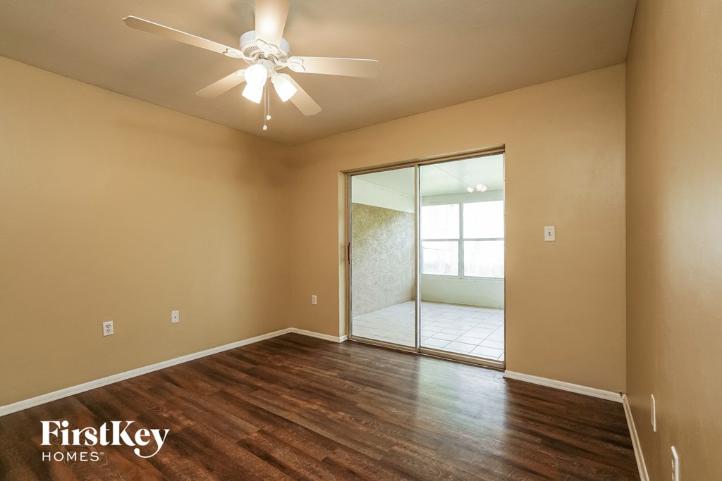 an empty room with a ceiling fan and a sliding glass door