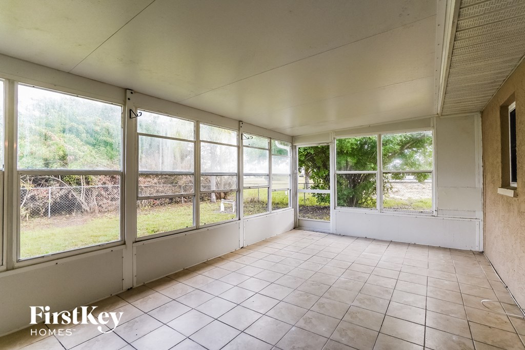 an empty living room with large windows and a tiled floor
