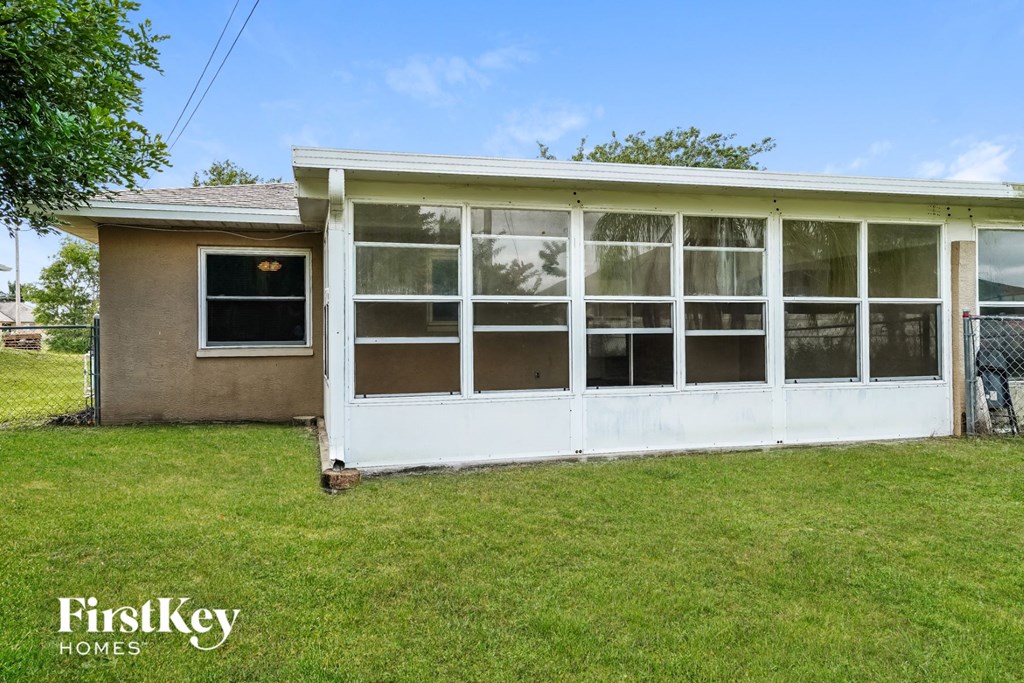 the back of a house with a white porch and grass