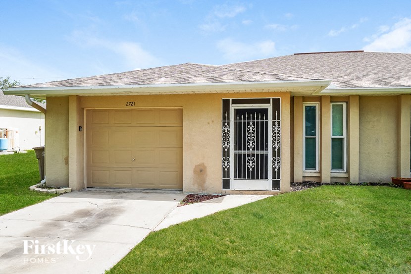 a beige house with a garage door and a lawn