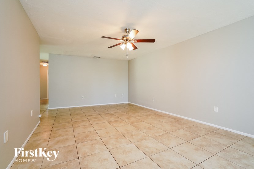 a empty living room with tile flooring and a ceiling fan