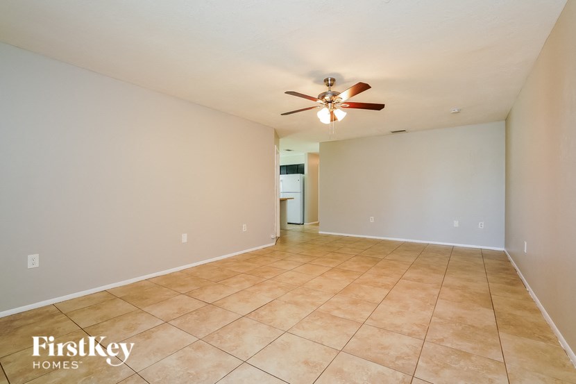 the spacious living room with tile flooring and a ceiling fan