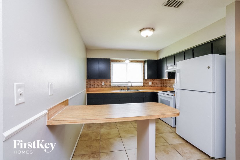 a kitchen with white appliances and a wooden table